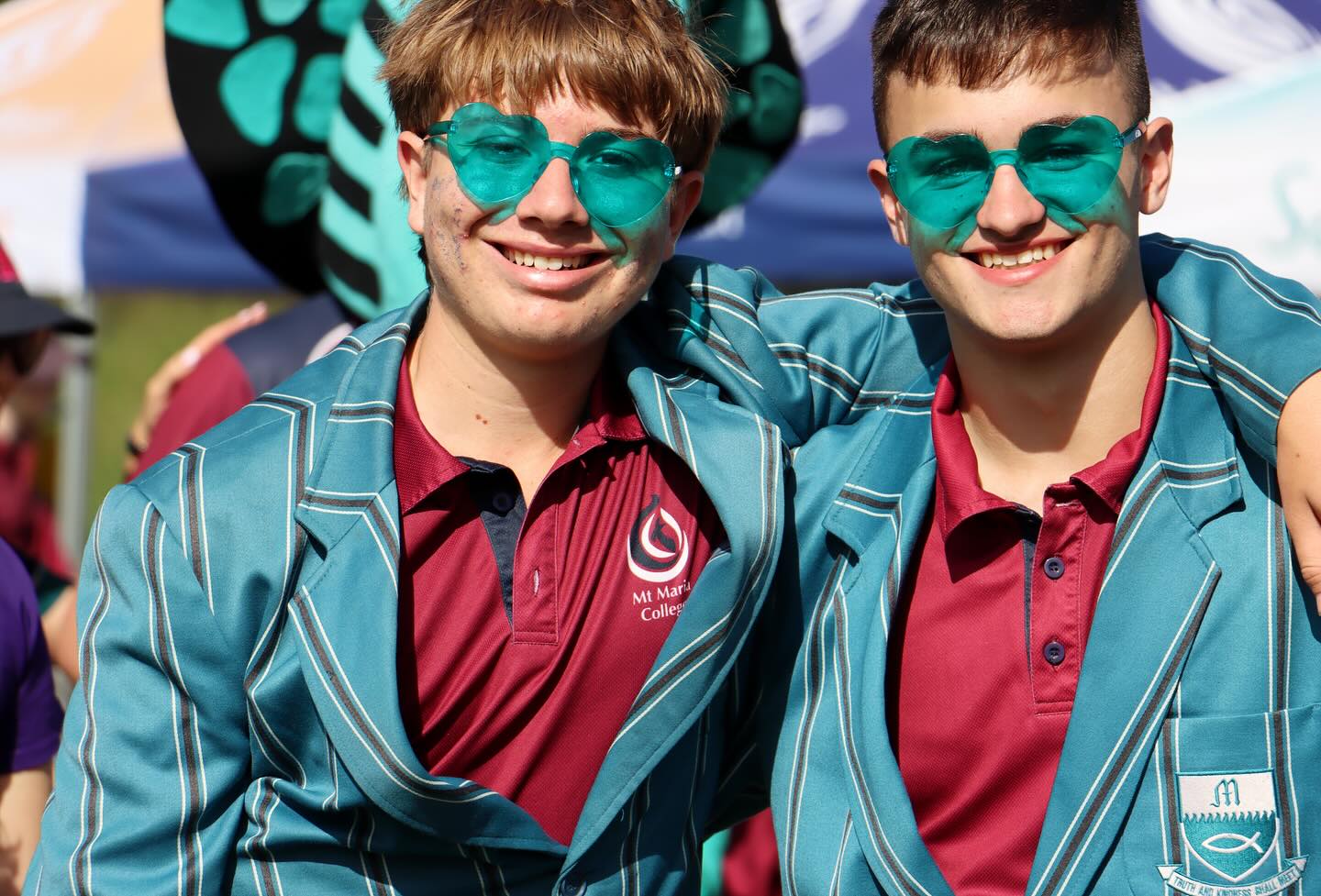 Two students wearing jackets stand together at a school event.