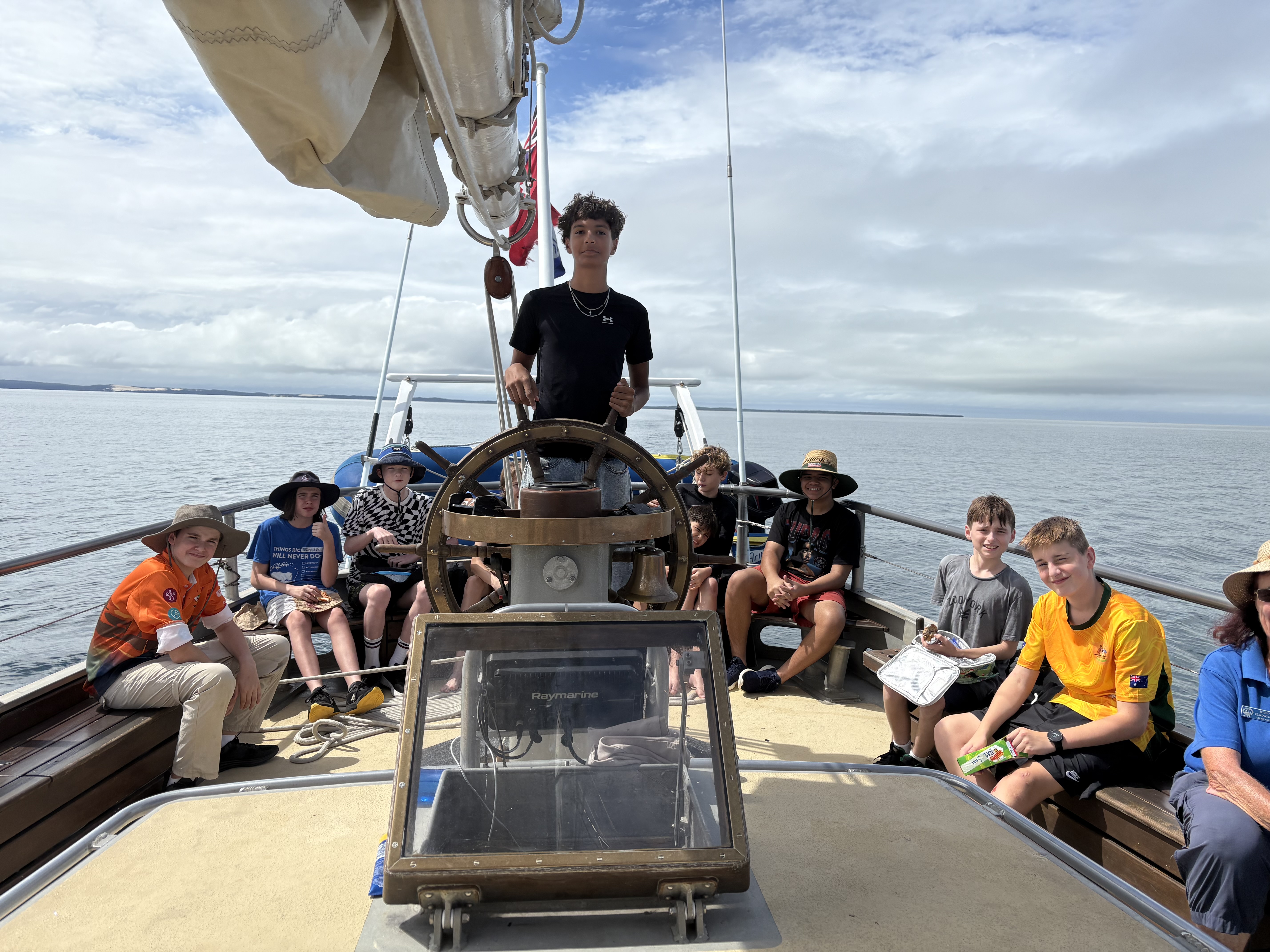 Students seated on the deck of a boat during an outdoor learning activity on the water.