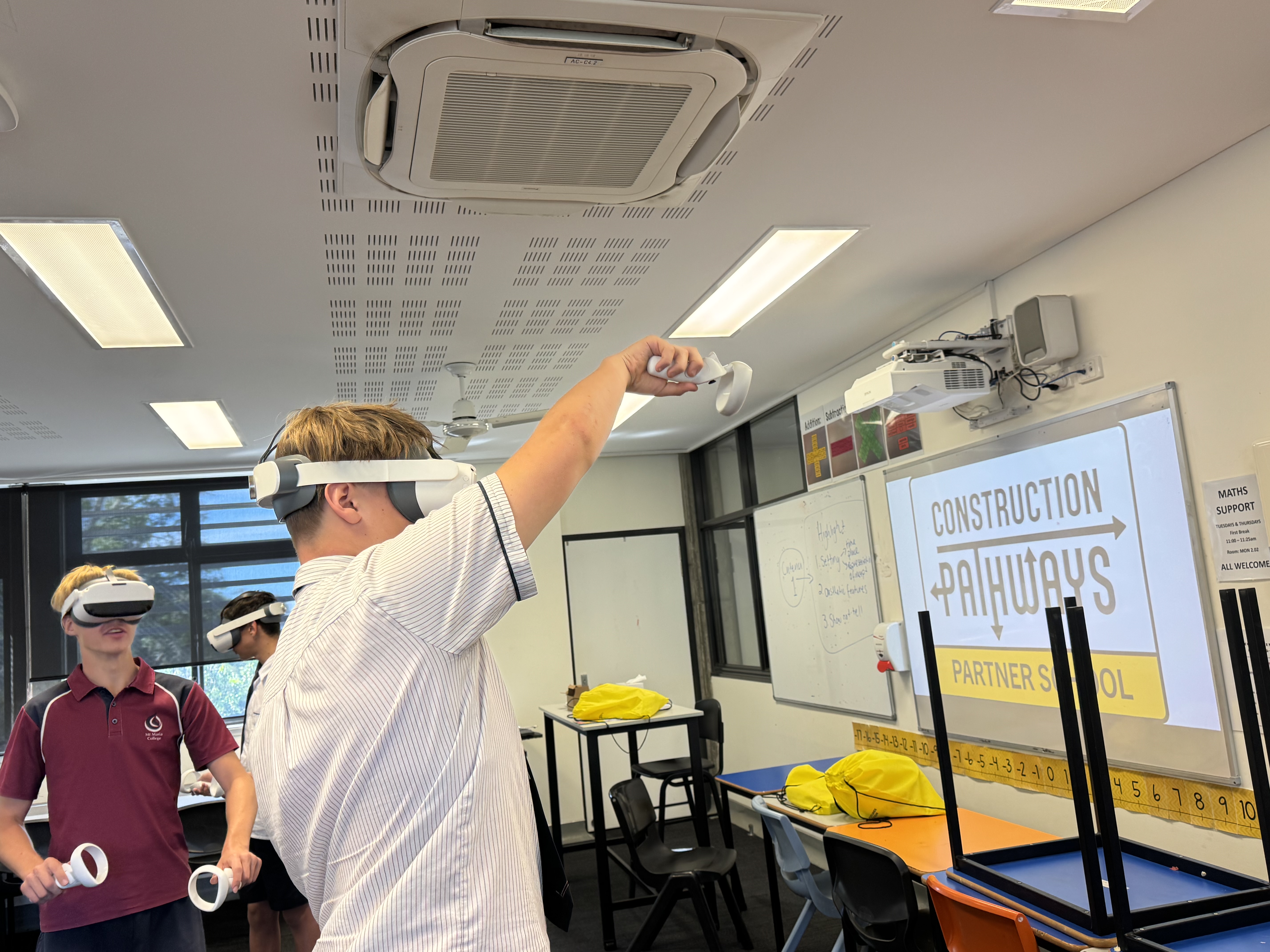 Secondary school students wearing virtual reality headsets participate in a construction pathways lesson in a classroom.