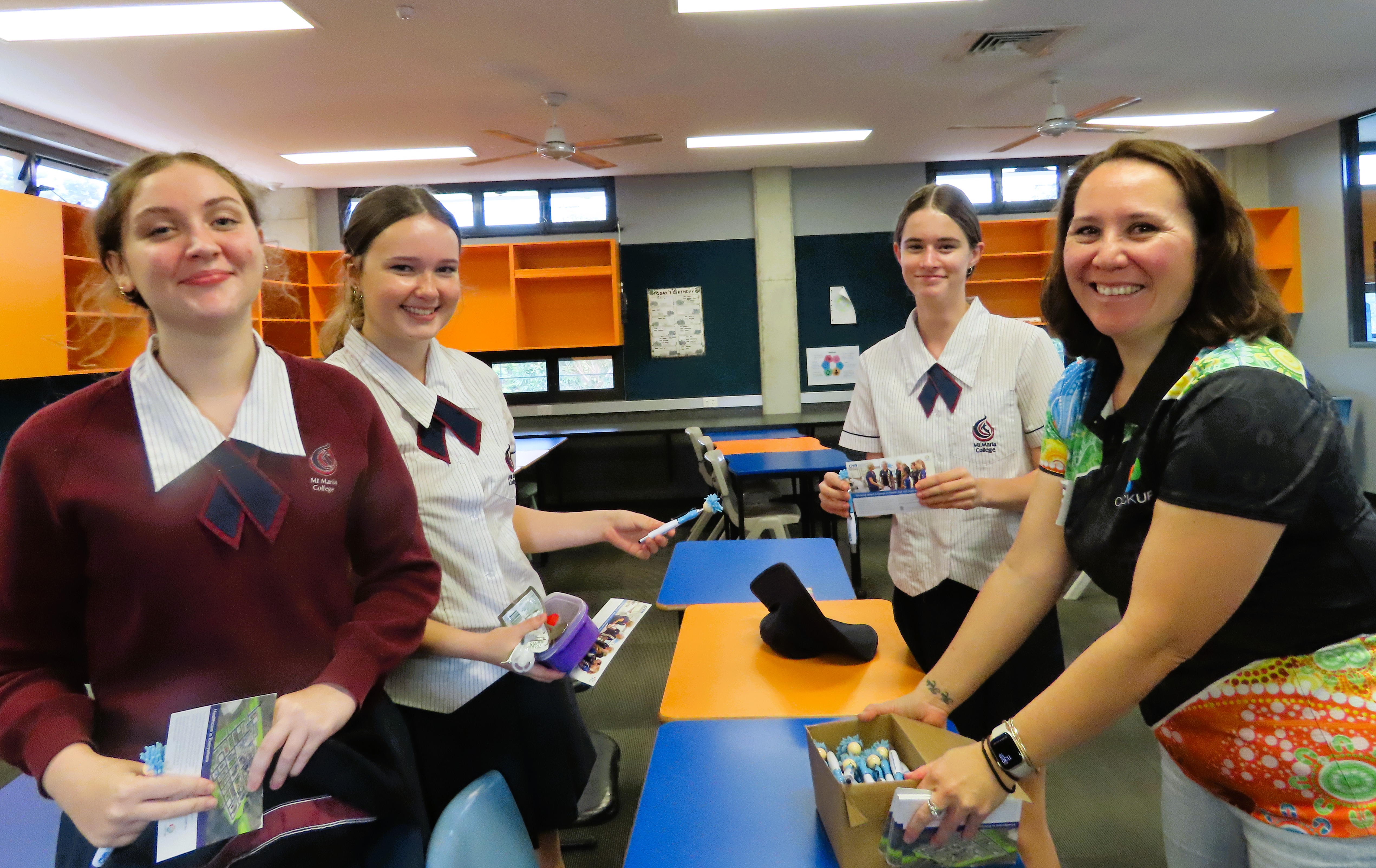 Secondary school students and an adult sort materials and equipment together in a classroom during a practical learning activity.