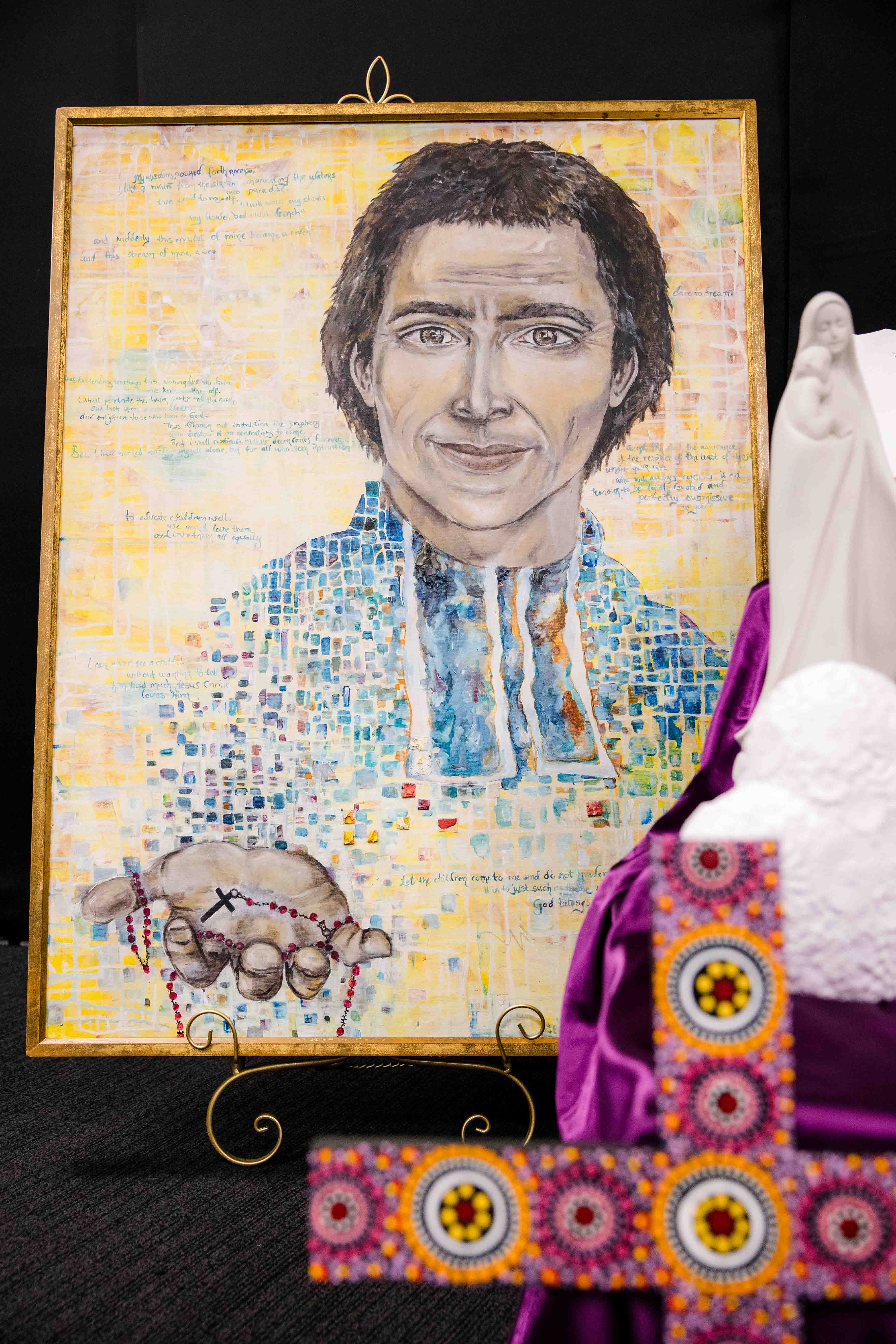 Framed portrait artwork displayed indoors, with religious symbols and decorative elements placed in the foreground.